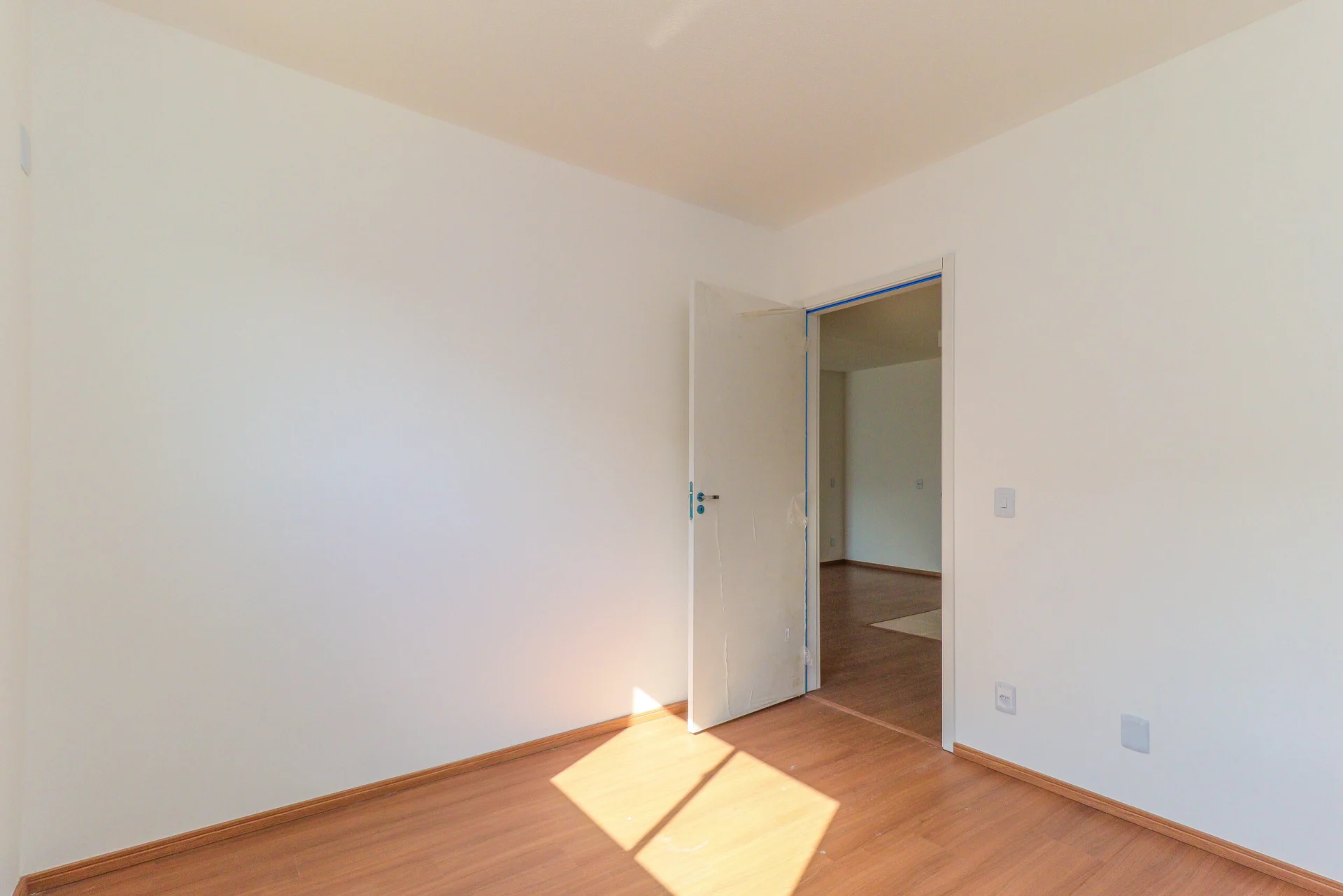 Foto de dormitório vazio com piso laminado em apartamento entregue do Residencial Capri