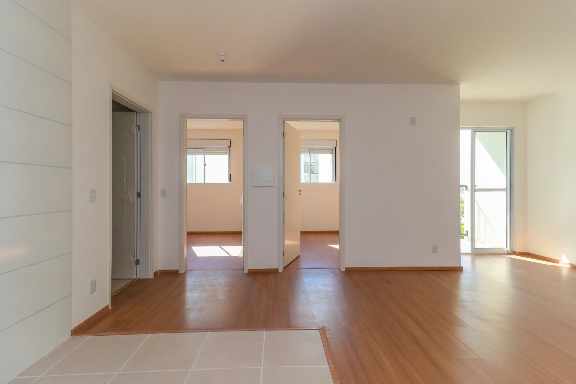 Foto da sala de um apartamento entregue e vazio do Residencial Capri, com as portas dos dormitórios